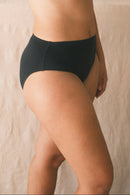 Woman wearing a black bikini against a neutral background